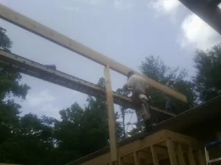 Carpenter setting a ridge beam over a new addition frame — Ice Dam Removal by Roofing Brothers in Mount Summit