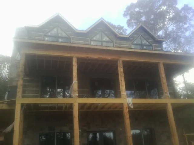 Dormers and porch framing on a large log home under construction — Roof Coating work by our crew in Mount Summit