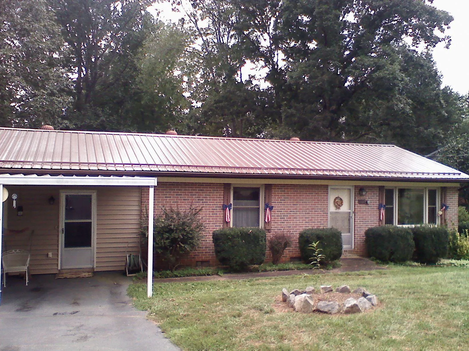 Bronze metal roof and carport on a brick ranch home — Roof Repair work by our crew in Mount Summit