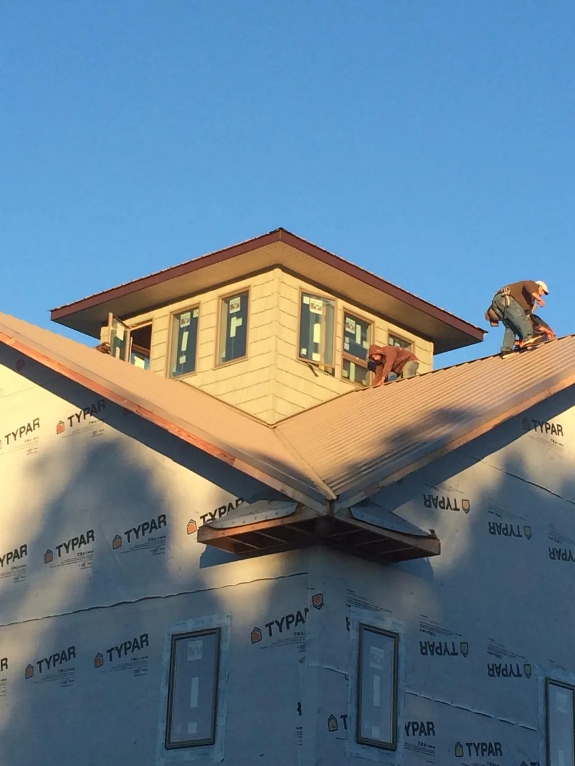 Roofers working around a rooftop cupola on a new metal roof at sunset — Roof Waterproofing in Mount Summit by Roofing Brothers